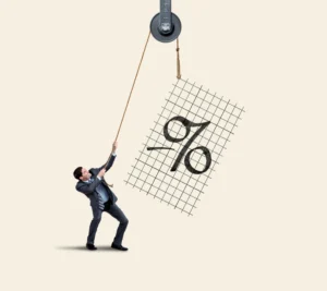 Businessman in a suit pulls a rope over a pulley, hoisting a tilted grid panel with a large percent sign, on a plain light background.
