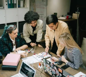 Group of young professionals collaborating around a table, reviewing color palettes and design samples during a creative meeting in an office.